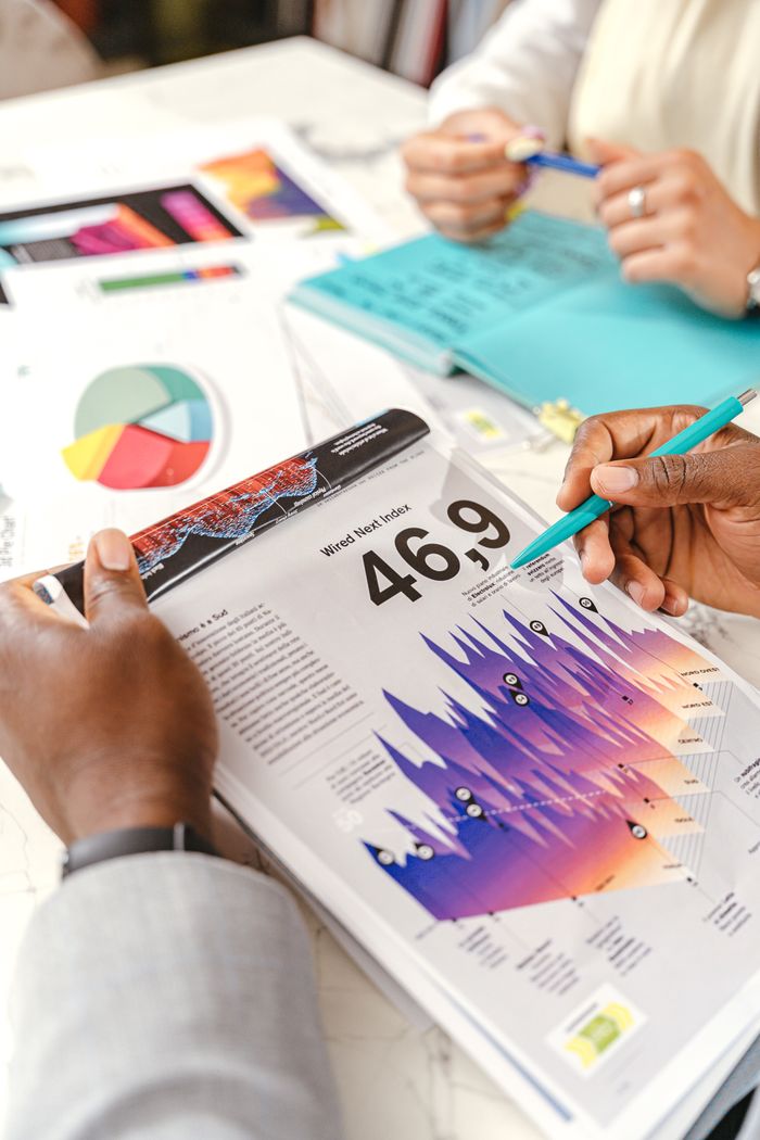 Des mains échangent autour de graphiques de données dynamiques pendant une réunion d'affaires, avec des documents et des schémas.